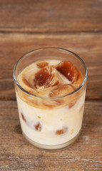 Iced coffee in glass on wooden background