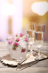 Ice cubes with rose flowers in glass bucket and two glasses