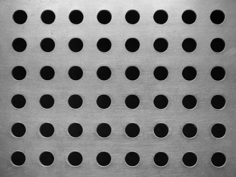 Metal plate with many circular holes background.