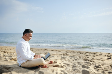 Fototapeta na wymiar man with laptop computer working on the beach