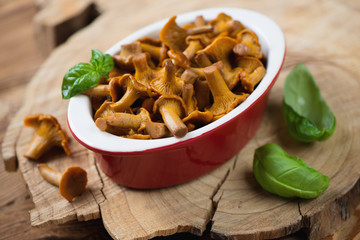 Glass bowl with marinated chanterelles over wooden background