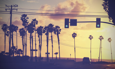 Vintage toned picture of palms by a street at sunset, California, USA.
