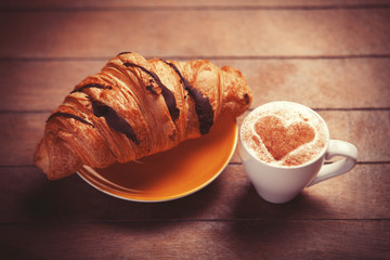 french croissant and cup of coffee on a wooden table