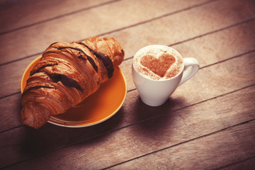 french croissant and cup of coffee on a wooden table