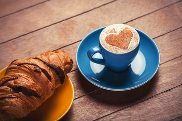 french croissant and cup of coffee on a wooden table