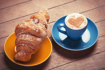 french croissant and cup of coffee on a wooden table