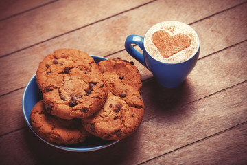 Cookie and cup of coffee on wooden table.