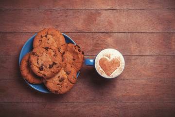 Cookie and cup of coffee on wooden table.