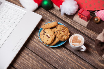 laptop and cookies wuth cup of coffee near christmas gifts.