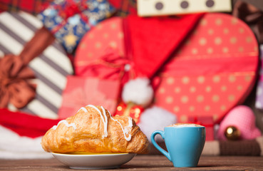Cup of coffee and croissant on christmas background.