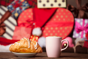 Cup of coffee and croissant on christmas background.