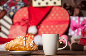 Cup of coffee and croissant on christmas background.