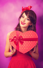Beautiful brunette girl with heart shape gift on violet backgrou