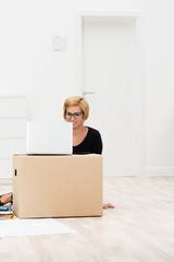 junge frau im büro mit laptop und karton
