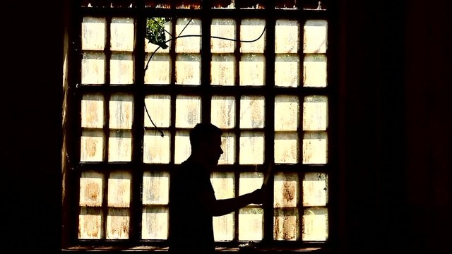 serial killer with knife passing by old window with bars