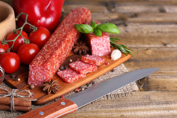 Tasty salami sausage and spices on wooden background