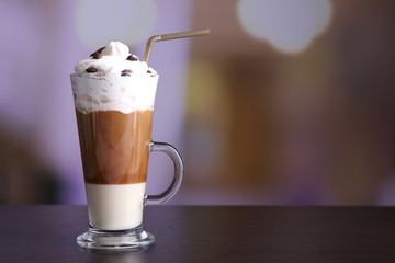Glass of coffee on color wooden table, on dark background