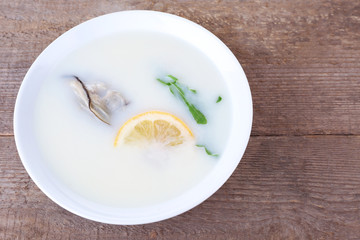 Tasty soup with oysters on wooden table