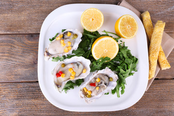 Tasty cooked oysters in shell on wooden table