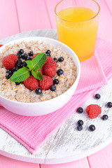 Tasty oatmeal with berries on table close-up