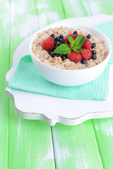 Tasty oatmeal with berries on table close-up