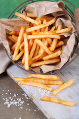 Tasty french fries in metal basket on table