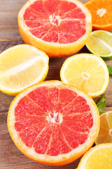 Different sliced juicy citrus fruits on wooden table