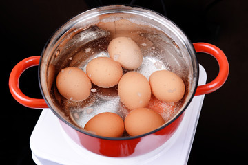 Eggs in boiling water in pan on electric hob