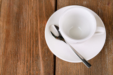 Empty cup with tea spoon on wooden background