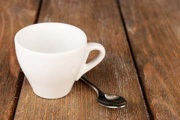 Fototapeta na wymiar Empty cup with tea spoon on wooden background