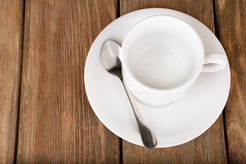 Empty cup with tea spoon on wooden background