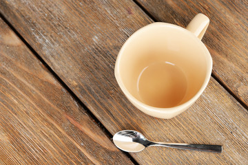 Empty cup with tea spoon on wooden background