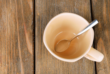 Empty cup with tea spoon on wooden background