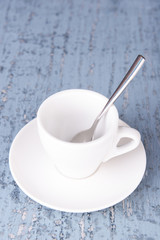 Empty cup with tea spoon on wooden background