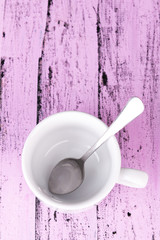 Empty cup with tea spoon on wooden background