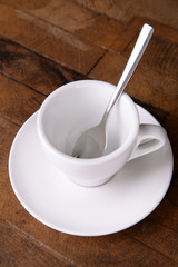 Empty cup with tea spoon on wooden background