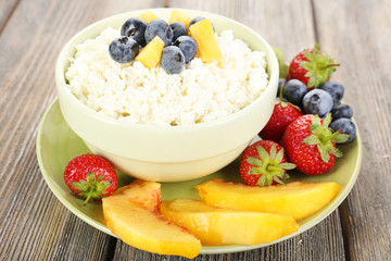 Cottage cheese with fruits and berries in bowl on wooden table