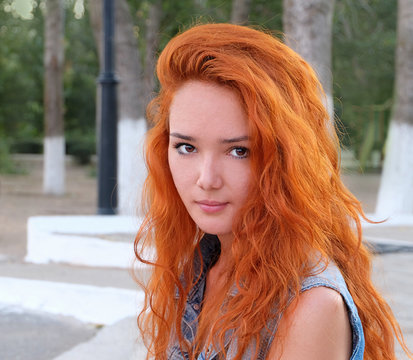 Head and shoulders image of a young women with red hair outdoors