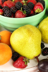 Ripe fruits and berries in bowl on table close up