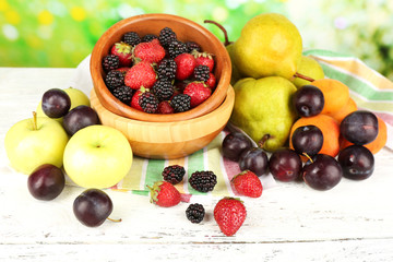 Ripe fruits and berries on table on bright background