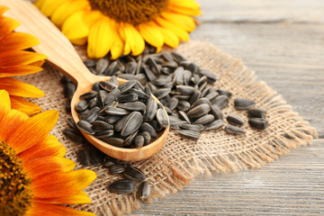 Naklejka premium Sunflowers and seeds with spoon on wooden background