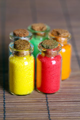 Bottles with colorful dry pigments on bamboo mat background