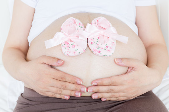 Pregnant belly with a pair of pink shoes