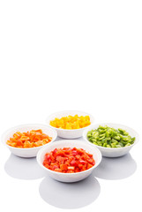 Fototapeta na wymiar Colorful chopped capsicums in white bowls over white background