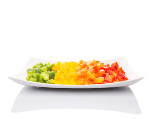 Colorful chopped capsicums in a plate over white background 