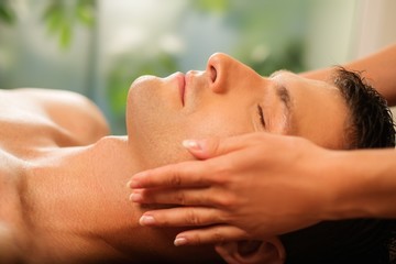 Handsome man having face massage in spa salon