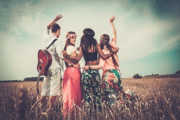Multi-ethnic hippie friends with guitar in a wheat field