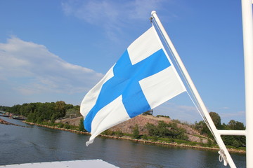 Die finnische Blaukreuzflagge vor einer Schäre bei Helsinki