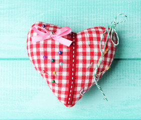 Fabric heart with color and safety pins on wooden background