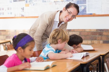 Fototapeta premium Pretty teacher helping pupil in classroom